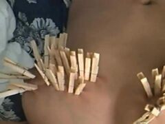 Submissive is lying on the bed and plays with small vibrator for her clitoris. Her large breasts covered with several dozen wooden clothespins. Then we see her sucking cock deep throating